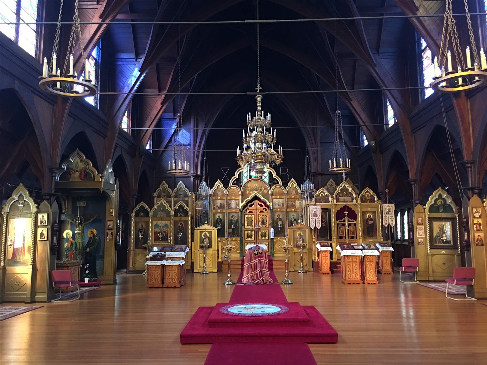 The interior of the Old Holy Virgin Cathedral in San Francisco, with its iconostasis, hanging chandeliers, and wooden vaulted ceiling.
